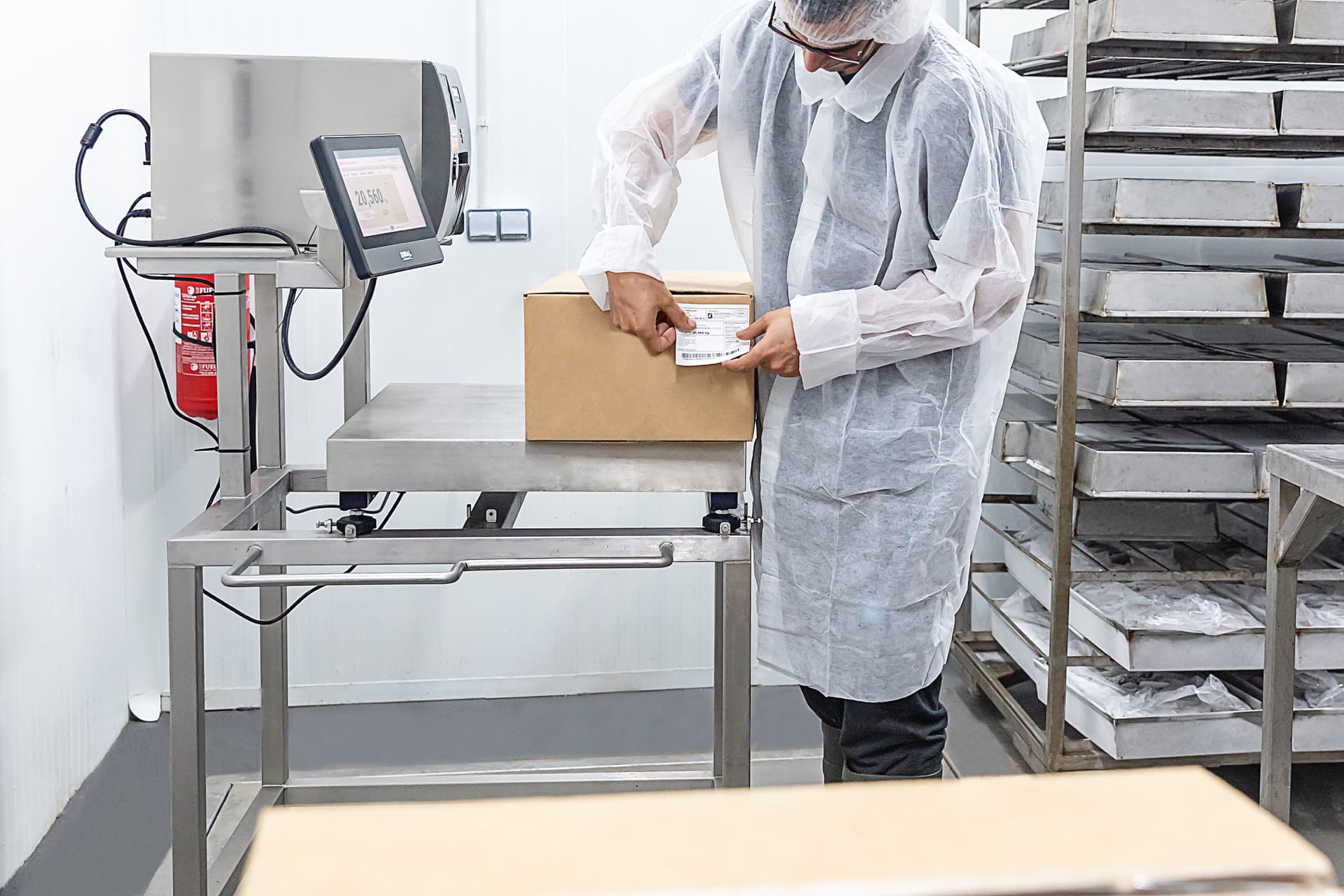 Operario etiquetando caja en báscula de control de peso