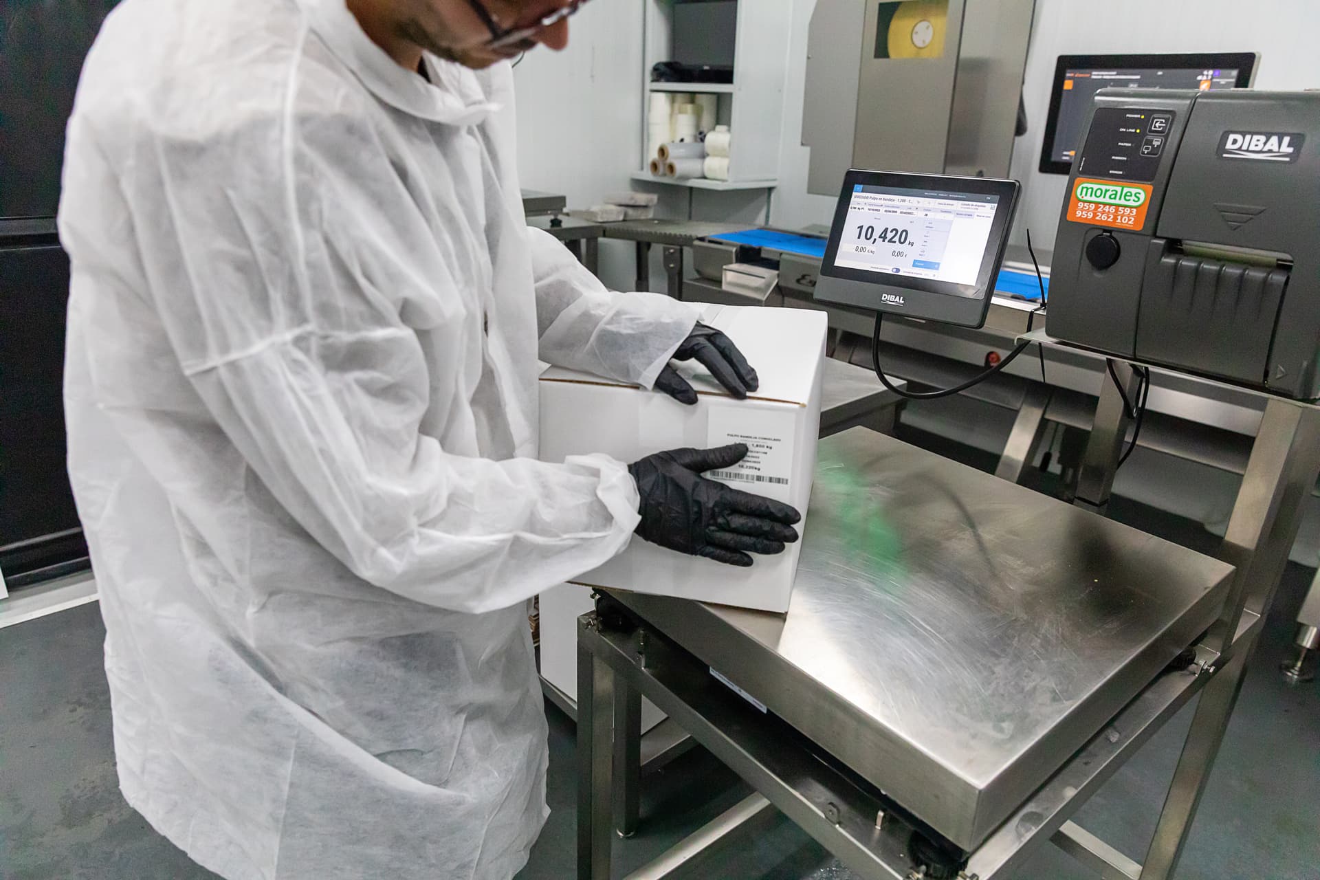 Operario pesando y etiquetando caja en máquina DIBAL